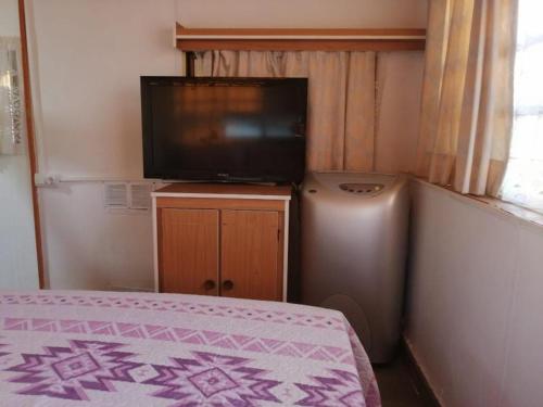 Kleines Zimmer mit einem TV und einem Bett in einem Zimmer in der Unterkunft House Camping Pasito Blanco in Maspalomas