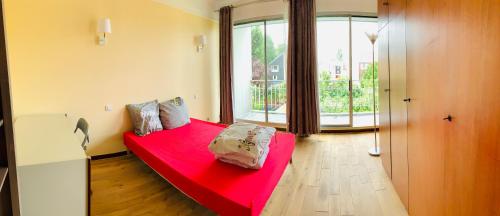 - un lit rouge dans une chambre avec une grande fenêtre dans l'établissement Confortable-House, à Vitry-sur-Seine
