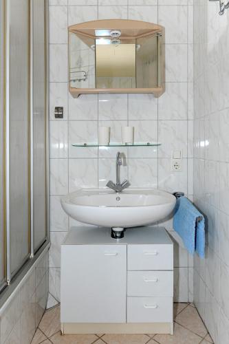 a white bathroom with a sink and a mirror at Ferienwohnung Weitblick in Holtgast