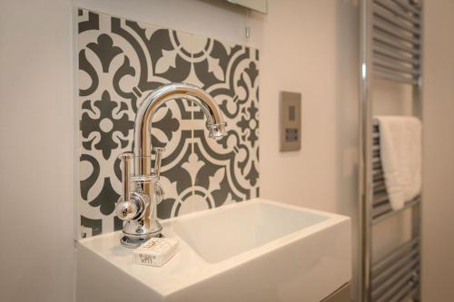 a bathroom with a white sink and a black and white wallpaper at Ravelston Grange - stylish, spacious garden flat in Old Town