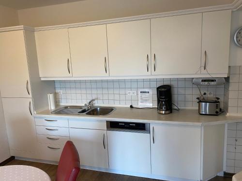 eine Küche mit weißen Schränken und einem Waschbecken in der Unterkunft Haus Mühlenberg in Arnsberg