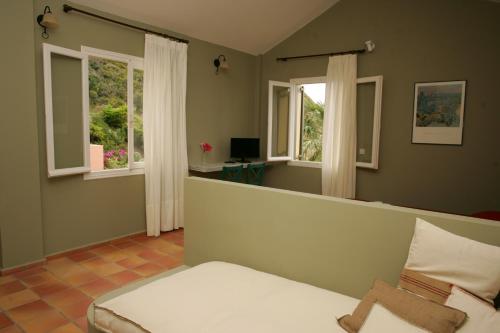a bedroom with a bed and two windows at Mounda Beach Hotel in Skala Kefalonias