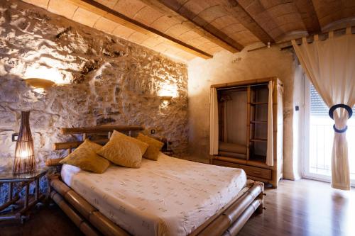 a bedroom with a bed and a stone wall at Le Jardin aux Sources in Brissac