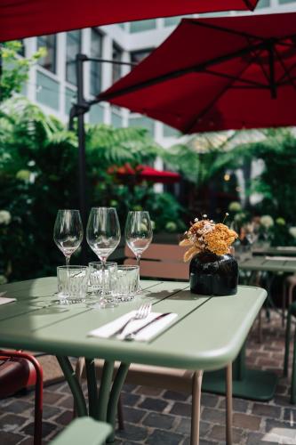 a table with wine glasses and a red umbrella at Le Grand Quartier in Paris