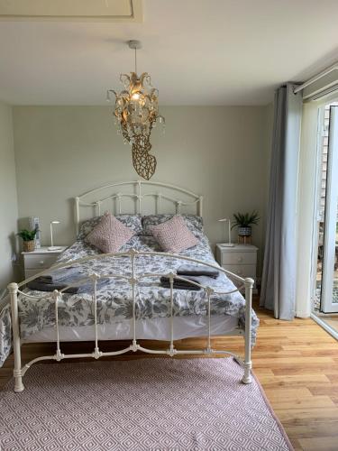 a bedroom with a bed and a chandelier at New Forest Chalet in Ibsley