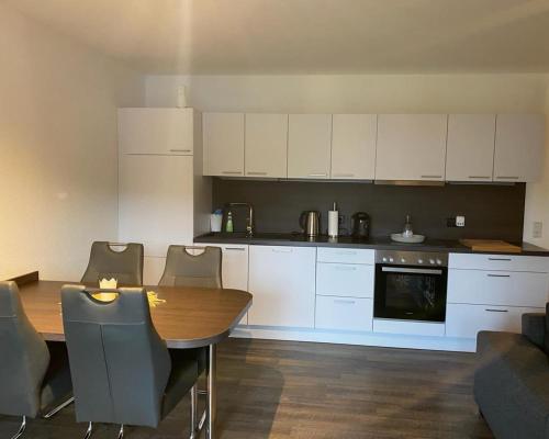a kitchen with a wooden table and white cabinets at Ferienwohnung am Tor zum Thüringer Wald in Plaue
