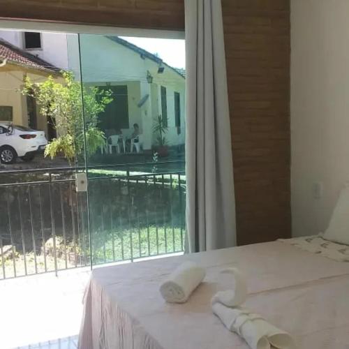 a bedroom with a bed and a large window at Recanto do Bosque in Magé