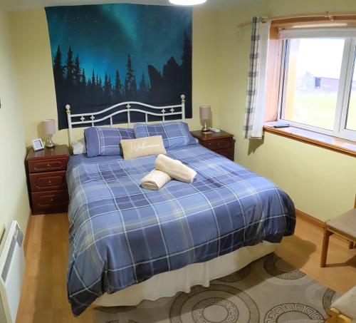 a bedroom with a blue bed with two towels on it at Hamnavoe John o Groats Hostel in John O Groats