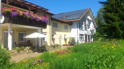 a house with a balcony with flowers and an umbrella at Ferienwohnungen Eichenhof in Kapellen-Drusweiler