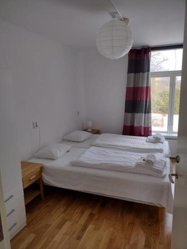 a white bedroom with a bed and a window at Hunnebergs Gård Hostel & Camping in Vargön