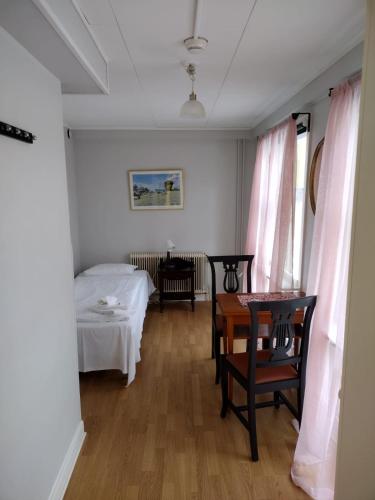 a room with a bed and a table and chairs at Hunnebergs Gård Hostel & Camping in Vargön