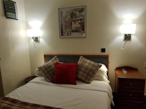 a bedroom with a bed with a red pillow on it at Linden Tree in Gloucester