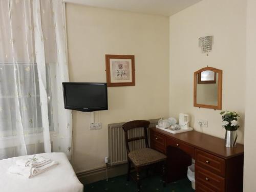 a hotel room with a desk and a tv on the wall at Linden Tree in Gloucester