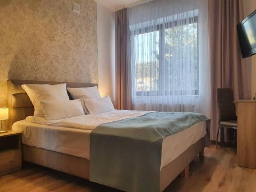 a bedroom with a bed with a window and a television at Janda Resort & Conference in Mszana Dolna