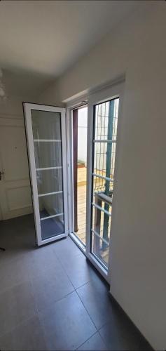 une chambre vide avec deux portes coulissantes et un balcon dans l'établissement 2 pièces terrasse plein coeur de Strasbourg, à Strasbourg