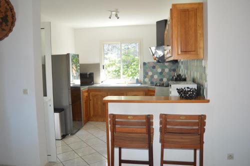 a kitchen with a counter and two chairs in it at Location saisonnière Les Hirondelles - Manapany in Saint-Joseph