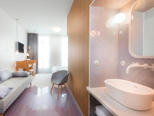 baño con lavabo y sofá en una habitación en Hotel le Lapin Blanc, en París
