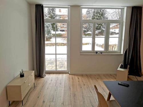 an empty living room with two windows and a table at City Lofts Tegernsee - Moderne Studios zentral gelegen in Bad Wiessee