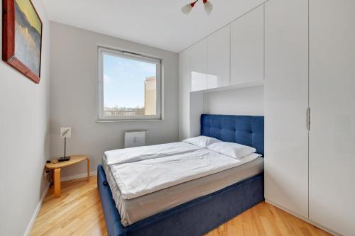 sypialnia z niebieskim łóżkiem i oknem w obiekcie Comfort Apartments Horyzonty w Gdańsku