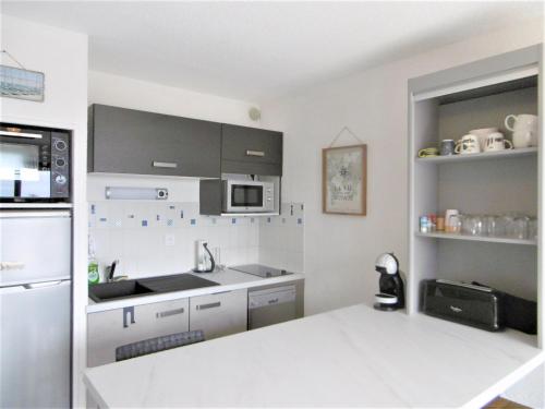 La cuisine blanche est équipée d'un évier et d'un réfrigérateur. dans l'établissement Appartement YOUN - à 500 m de la plage WIFI, à Sarzeau