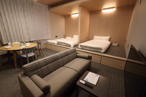 福岡市にあるWhite Crystal RoomAのソファ、ベッド、テーブルが備わるホテルルームです。
