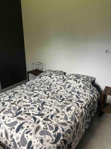 a bed with a black and white comforter in a bedroom at Suite indépendante au cœur d’un jardin arboré. in Montaut