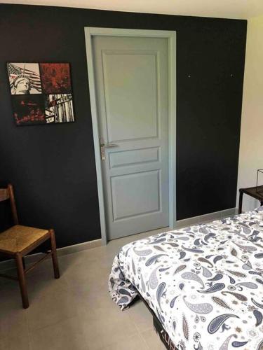 um quarto com uma cama, uma porta e uma cadeira em Suite indépendante au cœur d’un jardin arboré. em Montaut