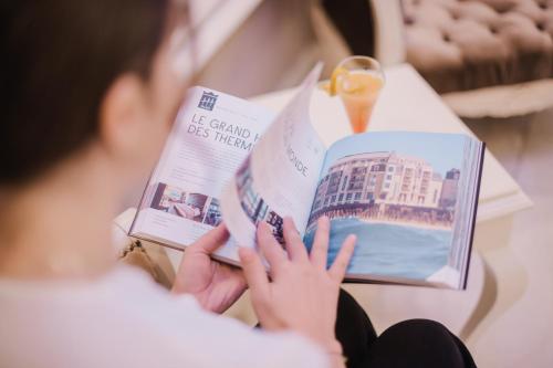 a woman reading a book on a table at Lot Boutique Hotel by Hotels and Preference in Tirana