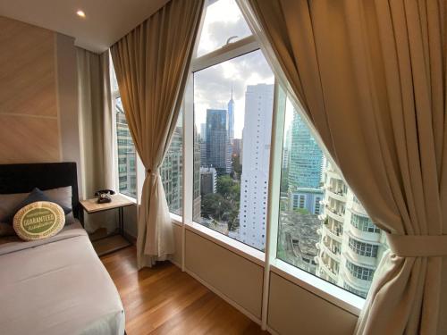 クアラルンプールにあるSky Suites KLCC by GENESISの街の景色が見える大きな窓のある寝室