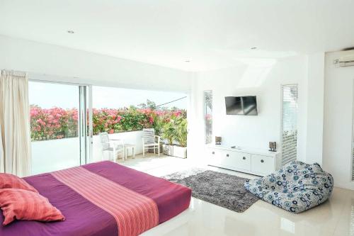 ein weißes Schlafzimmer mit Bett und Balkon in der Unterkunft Rapture Surfcamps Green Bowl in Ungasan