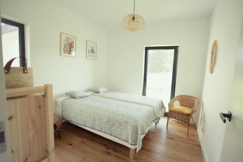 a white bedroom with a bed and a chair at Dom na Cuplu in Serock