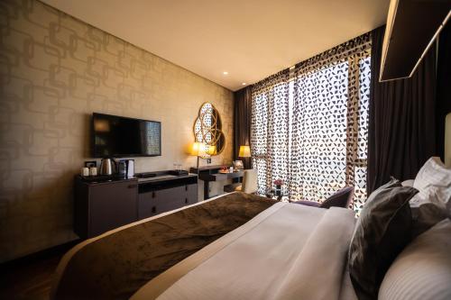 a bedroom with a bed and a television and a window at Lancaster Plaza Beirut in Beirut