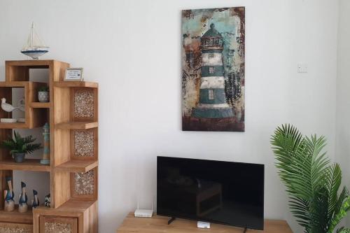 a living room with a television and a painting on the wall at Upmarket, new, stunning 3 bedroom apartment close to the beach! in Pereybere