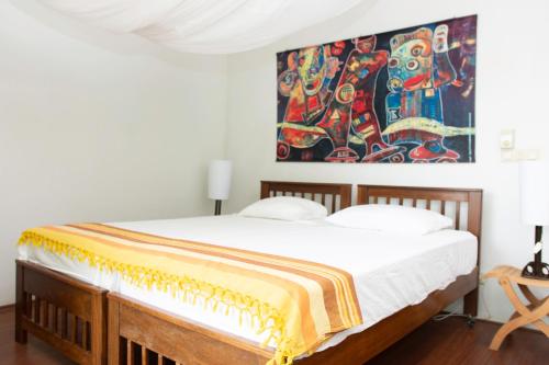 1 dormitorio con 1 cama con una pintura en la pared en Boom Apartments en Paramaribo