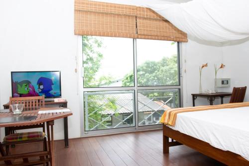 Schlafzimmer mit einem Bett, einem Schreibtisch und Fenstern in der Unterkunft Boom Apartments in Paramaribo