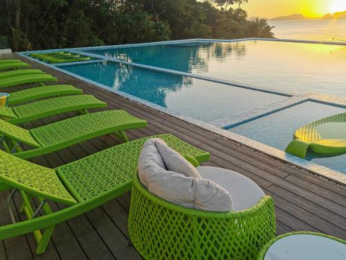 una piscina con sillas verdes y una piscina en Lime Resort El Nido en El Nido