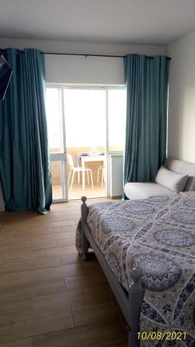 een slaapkamer met een bed met groene gordijnen en een balkon bij Sol e Praia Alvor 2 in Alvor