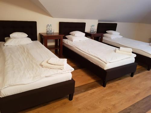 three beds in a room with wooden floors at Dworek Saski in Radom