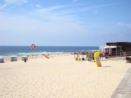 a beach with people sitting on the sand and the ocean at Residencial do Mar in Praia de Mira