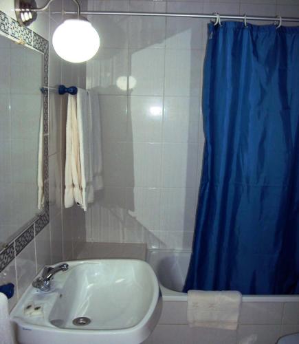 a bathroom with a sink and a blue shower curtain at Residencial do Mar in Praia de Mira
