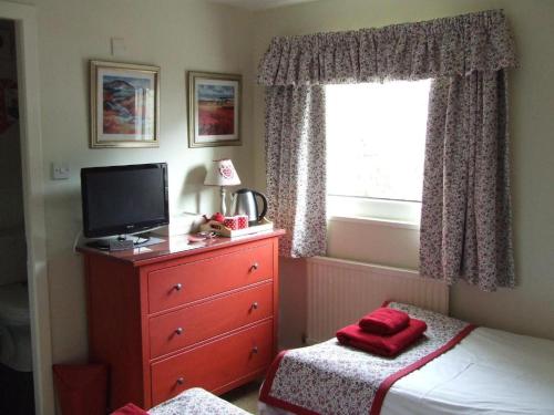 
a bedroom with a bed and a dresser at Dana Villa Guest House in Oban
