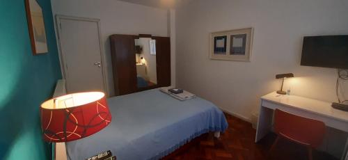 a bedroom with a bed and a desk with a lamp at Sonia's Homestay in Rio de Janeiro