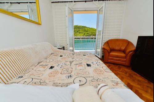 a bedroom with a bed and a chair and a window at Apartment Niksa in Novigrad Dalmatia