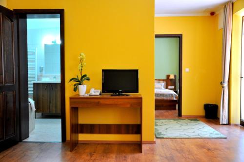 a living room with yellow walls and a television on a desk at Forster Vadászkastély és Szálloda in Bugyi