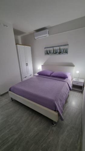 um quarto com uma cama grande e lençóis roxos em Room Airport Split em Kaštela