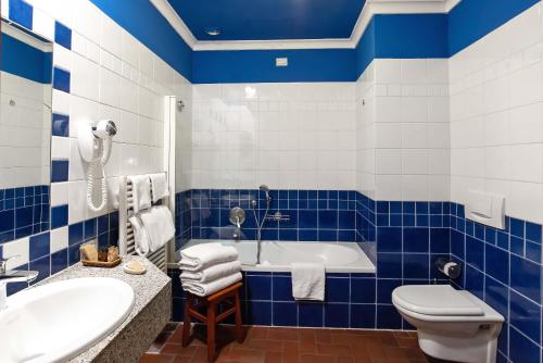 a blue and white bathroom with a tub and a toilet at Hotel Porta Faenza in Florence