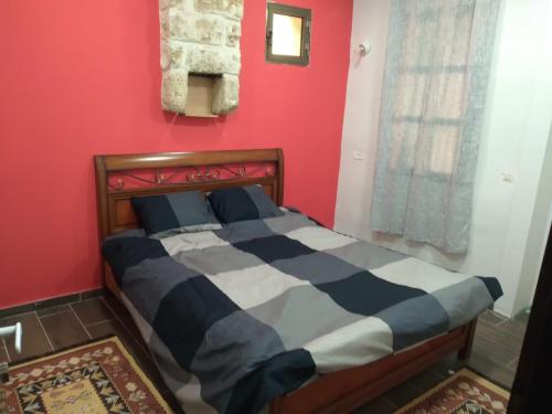 a bed in a room with a red wall at BenGurion 25 Apartment in Haifa