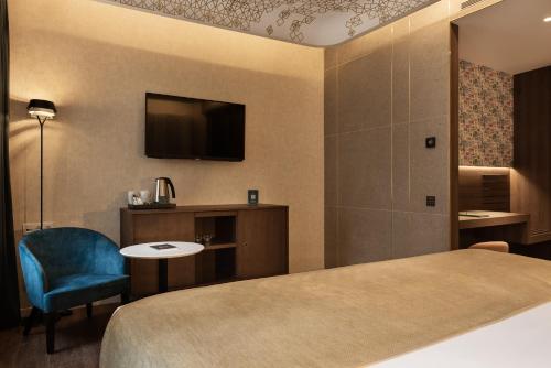 a hotel room with a bed and a chair and a tv at Áurea Palacio de Correos by Eurostars Hotel Company in Logroño