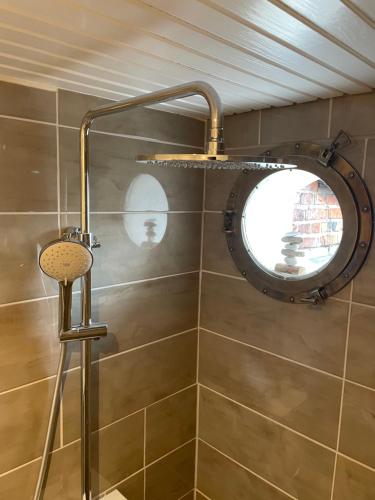 a bathroom with a shower with a round mirror at Doddy‘s Stuuv in Niesgrau