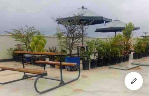 a picnic table with an umbrella and benches at Asuila studio - Kiambu road Nairobi in Nairobi